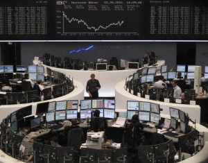 Traders are pictured at their desks in front of the DAX board at the Frankfurt stock exchange